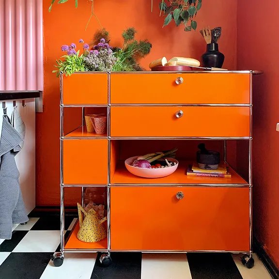 USM Haller wagen in Reinorange. Mit Blumen dekoriert.